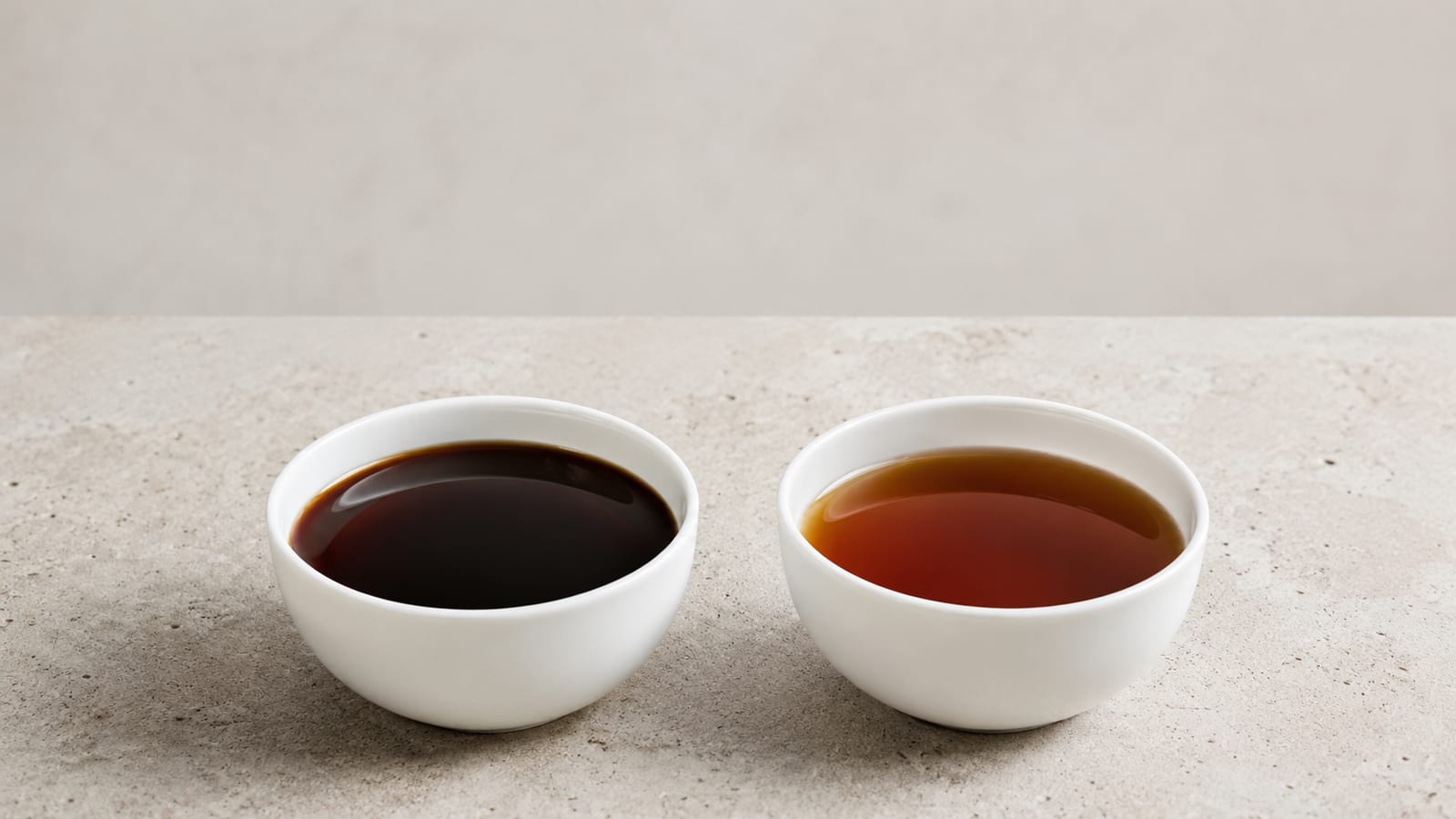 Two coffee samples in white cupping bowls showing color and clarity differences