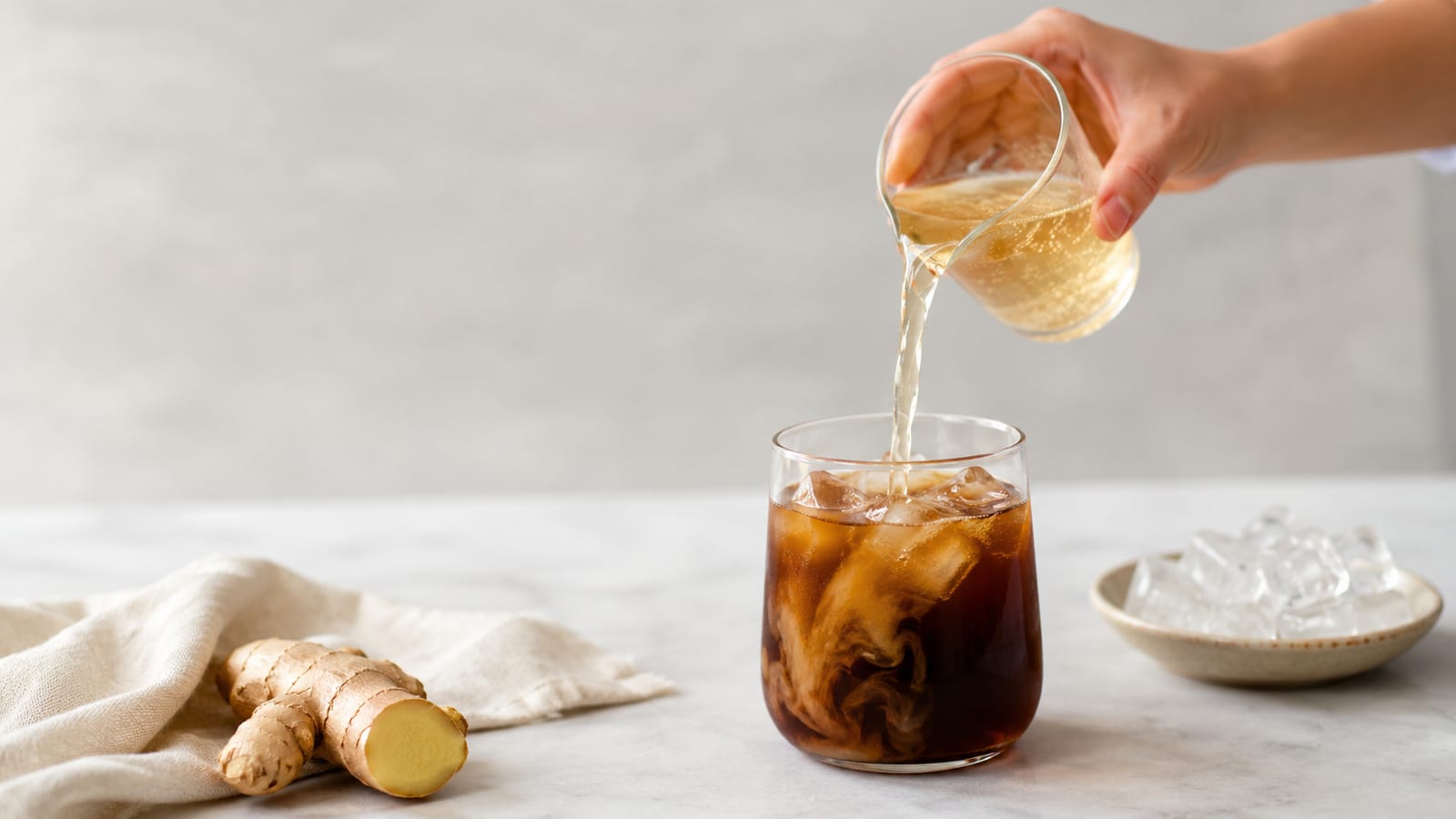 Ginger Ale Iced Coffee: A Bubbly & Spicy Twist poured into an iced glass beside ginger root