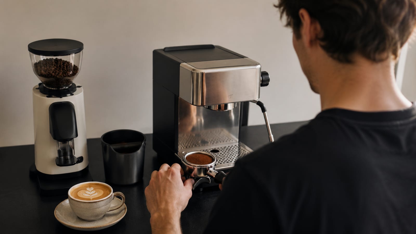 is an espresso machine worth the investment, viewed over a person’s shoulder with grinder and latte