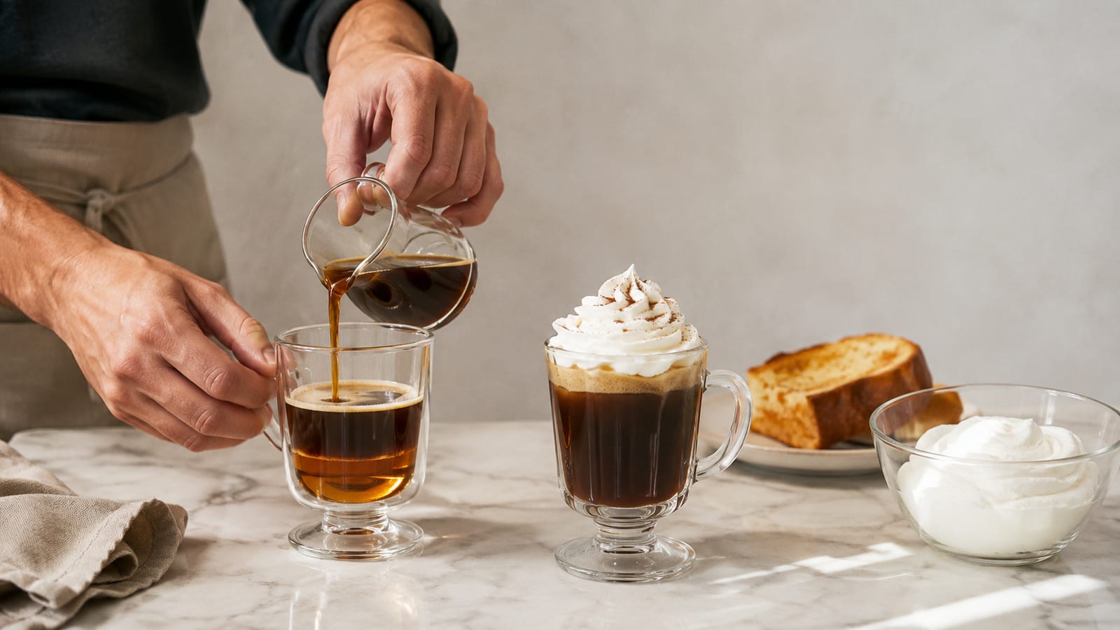 Hands preparing hot coffee cocktail with brandy, orange liqueur, and whipped cream