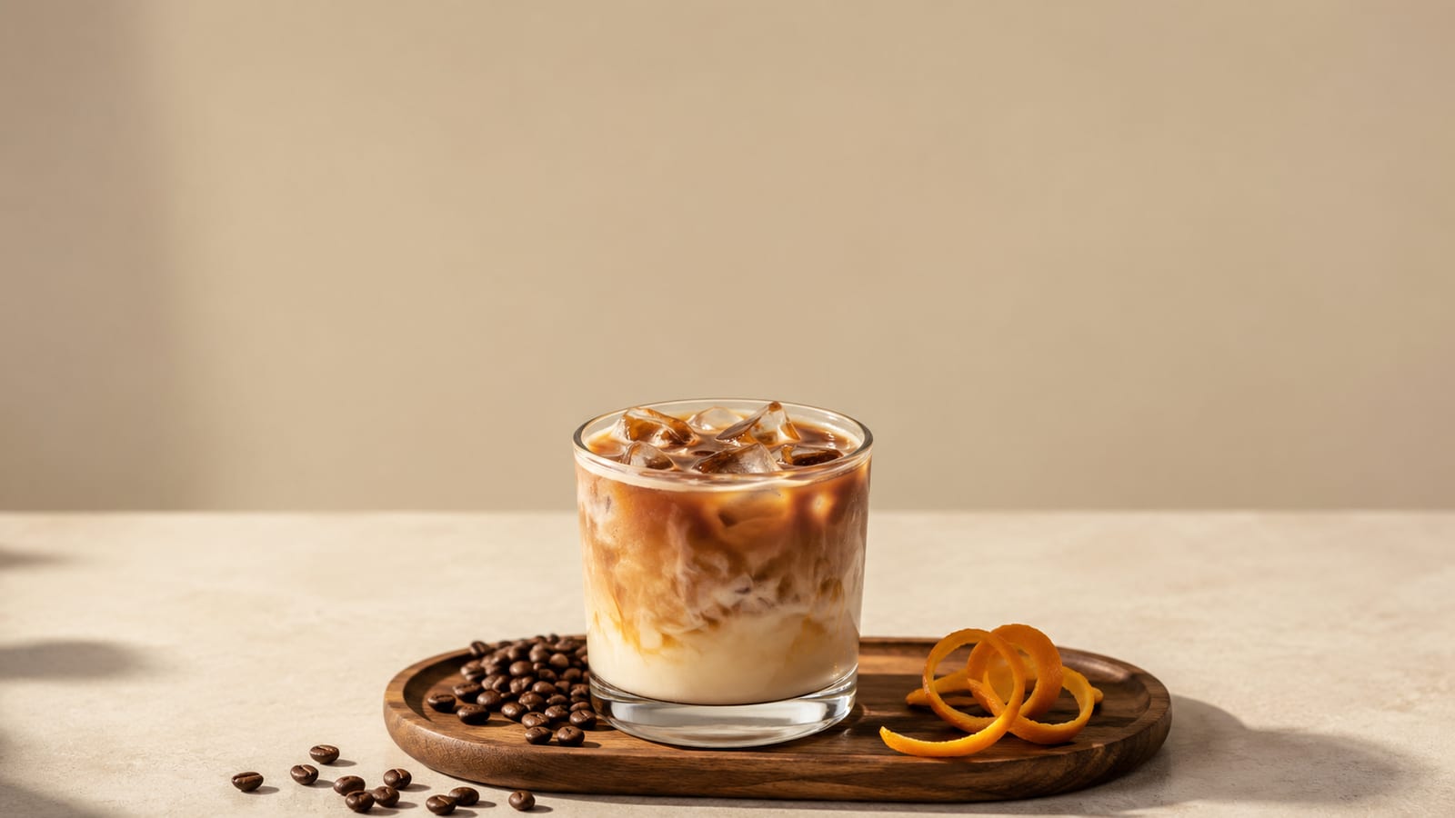 Iced Monte Cristo coffee with cream and orange garnish among coffee beans and ice